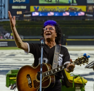 Ides of March lead singer Jim Peterik leads his band in the national anthem at the  Chicago White Sox baseball game against the Los Angeles Angels on Monday, June 30, 2014, in Chicago. (AP Photo/Matt Marton)